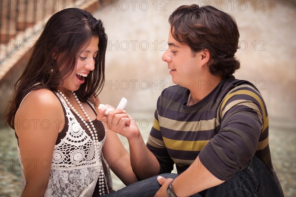 Hispanic man proposing with an engagement ring to his love