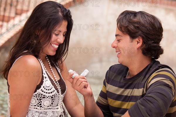 Happy hispanic man proposing with an engagement ring to his love