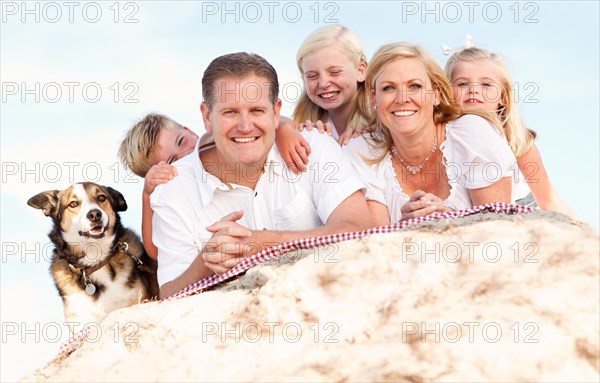 Happy caucasian family and dog portrait at the beach one sunny afternoon
