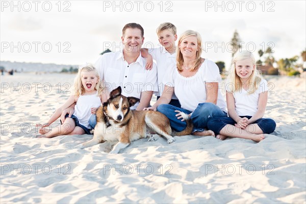 Happy caucasian family and their dog at the beach