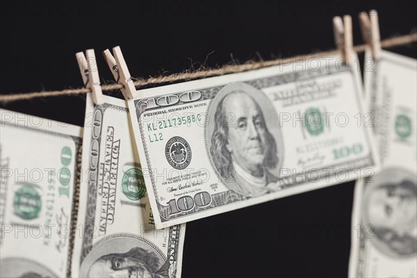 Hundred dollar bills hanging from a clothesline on a dark background