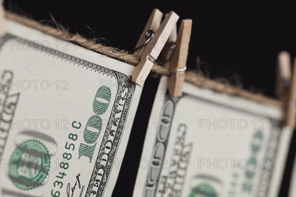 Hundred dollar bills hanging from a clothesline on a dark background