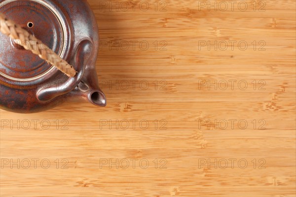Tea pot and bamboo textured surface background with plenty of room for text