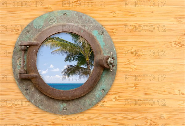 Antique porthole with tropical beach view on a bamboo wall background