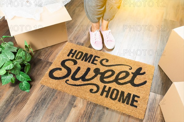 Woman in pink shoes and sweats standing near home sweet home welcome mat