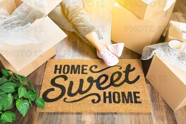 Woman wearing sweats relaxing near home sweet home welcome mat