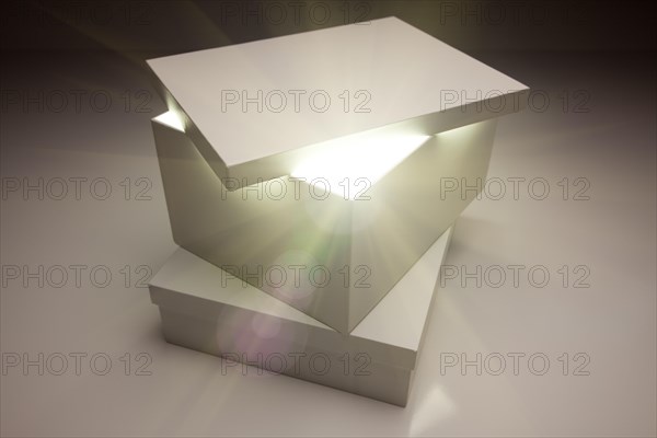 White box with lid revealing something very bright on a grey background