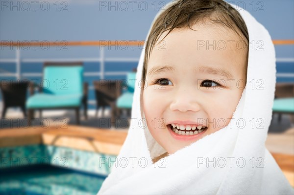 Happy cute mixed-race chinese and caucasian boy on cruise ship wrapped in A towel