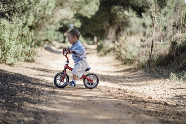 Cute toddler riding his bicycle on the dirt road