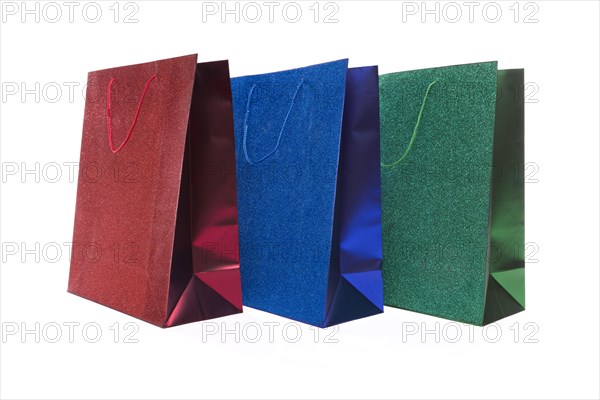 Set of three multicolored glitter gift bags on a white background