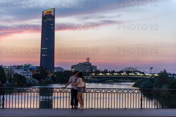 Couple standing on the bridge at sunset and kissing