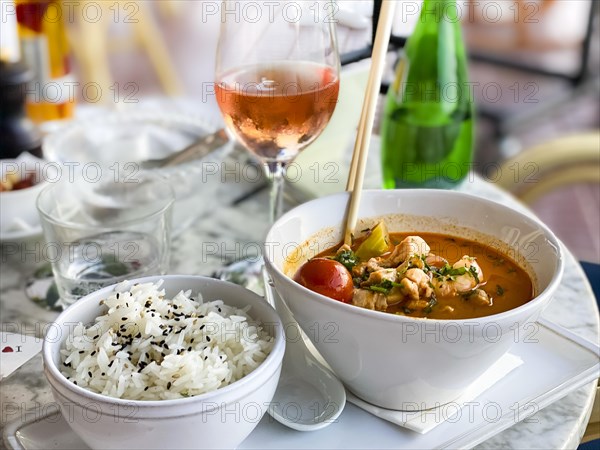 Asian soup in coconut sauce with shrimp and fish with rice