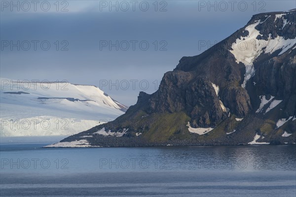 Green cliff in the glacier covered moutains of Franz Josef Land archipelago