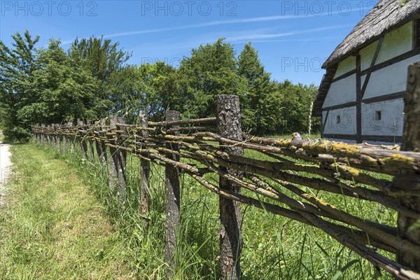 Wooden fence connected with thin branches in wickerwork