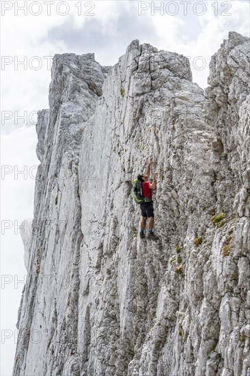 Young man climbing a vertical rock face without a rope