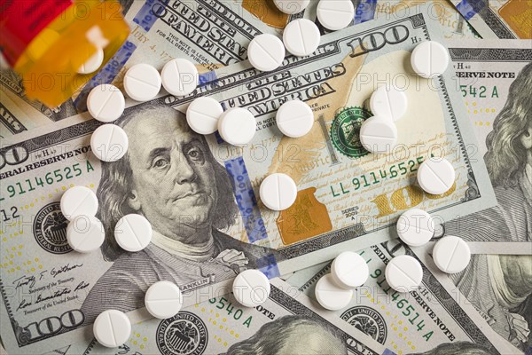 Medicine pills scattered on newly designed U.S. one hundred dollar bills