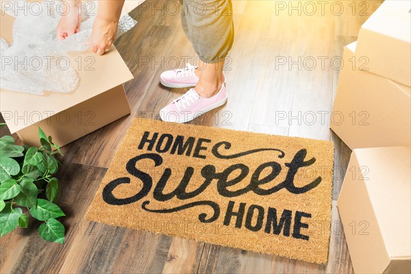 Woman in pink shoes and sweats unpacking near home sweet home welcome mat