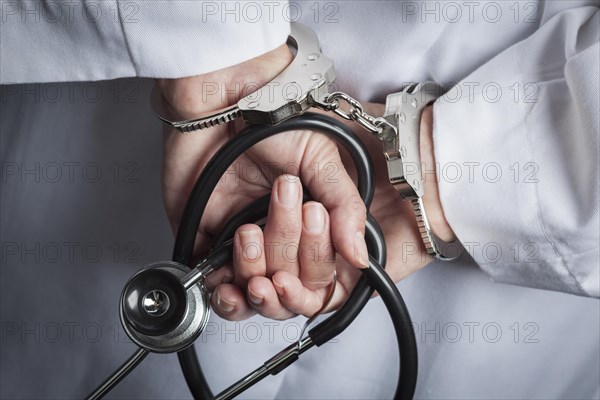 Female doctor or nurse in handcuffs and lab coat holding stethoscope