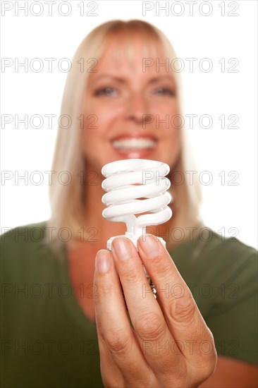 Attractive blonde woman holds energy saving light bulb isolated on a white background with narrow depth of field