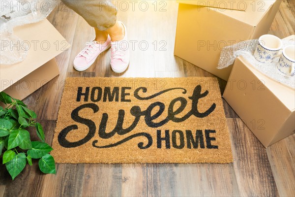 Woman in pink shoes and sweats standing near home sweet home welcome mat