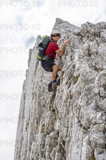 Young man climbing a vertical rock face without a rope