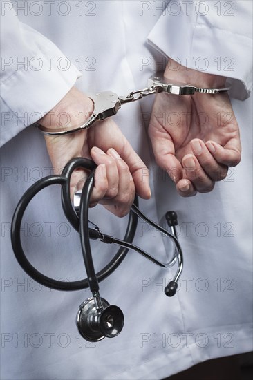 Female doctor or nurse in handcuffs and lab coat holding stethoscope