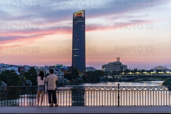 Couple standing on the bridge at sunset