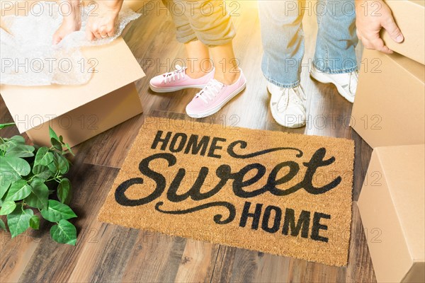 Man and woman unpacking near home sweet home welcome mat