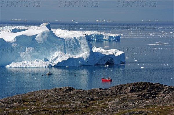 Red boat in front of big icebergs