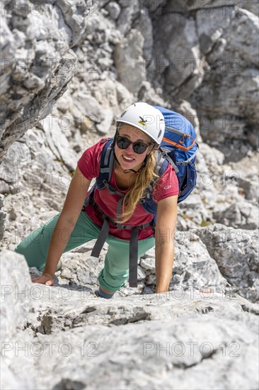 Young female hiker climbing with helmet