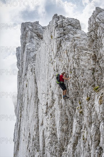 Young man climbing a vertical rock face without a rope