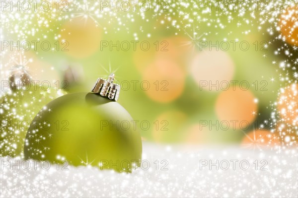 Beautiful matt green christmas ornaments on snow flakes over an abstract snow and light background with room for your own text