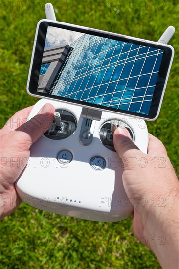 Hands holding drone quadcopter controller with corporate building on screen