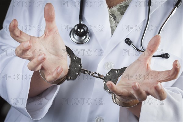 Female doctor or nurse in handcuffs wearing lab coat and stethoscope