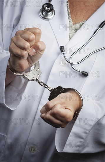 Female doctor or nurse in handcuffs wearing lab coat and stethoscope