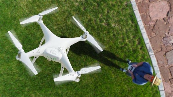 Drone quadcopter (UAV) in air above pilot with remote controller