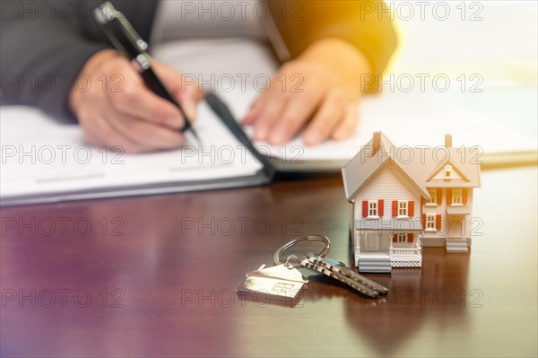 Woman signing real estate contract papers with house keys