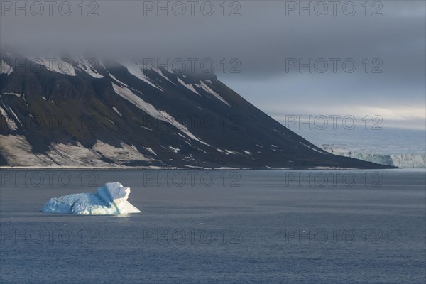 Iceberg floating before the flat table mountains covered with ice