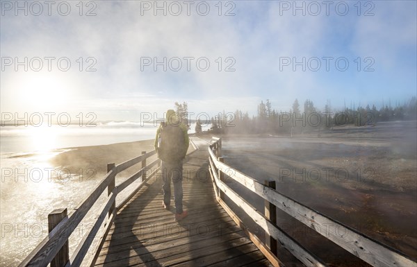 Hiker on boardwalk between steaming hot springs