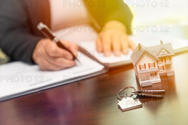 Woman signing real estate contract papers with house keys