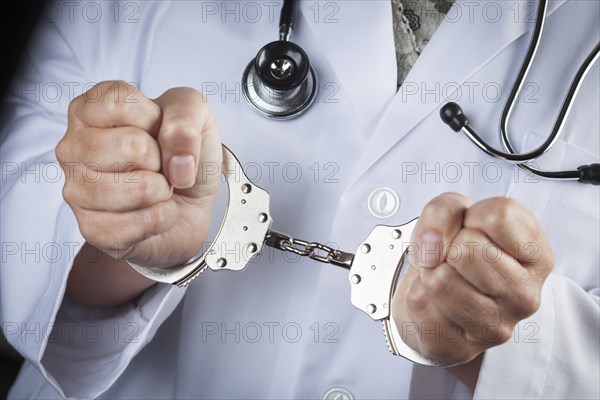 Female doctor or nurse in handcuffs wearing lab coat and stethoscope
