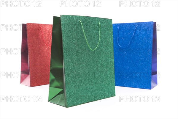 Set of three multicolored glitter gift bags on a white background
