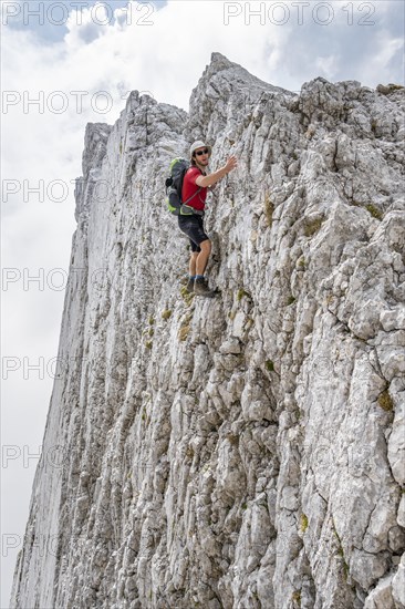 Young man climbing a vertical rock face without a rope