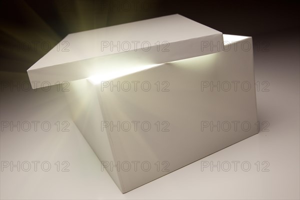 White box with lid revealing something very bright on a grey background