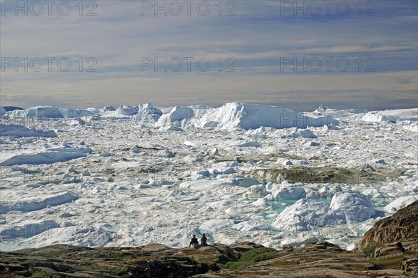 People in front of icebergs in fjord