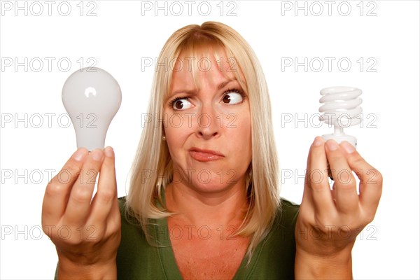 Funny faced woman holds energy saving and regular light bulbs isolated on a white background