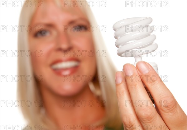 Attractive blonde woman holds energy saving light bulb isolated on a white background with narrow depth of field