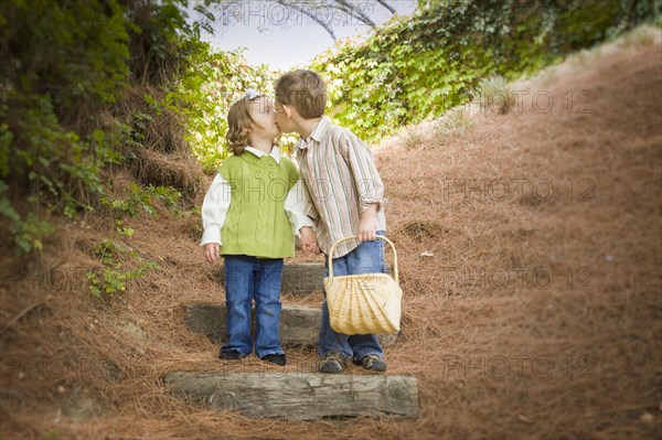 Adorable brother and sister children with basket kissing outside