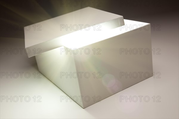 White box with lid revealing something very bright on a grey background