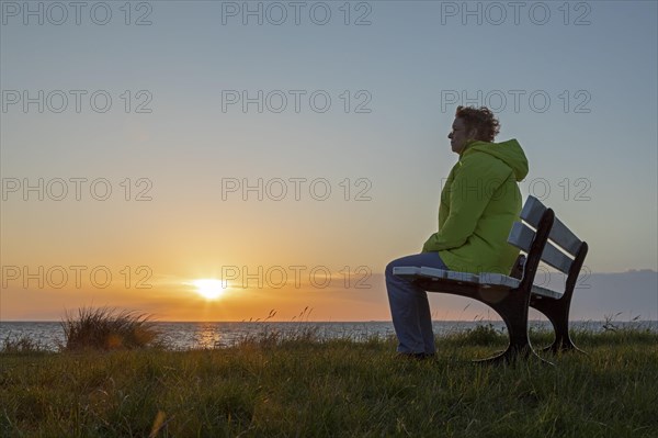 Woman enjoying the sunset on a bench